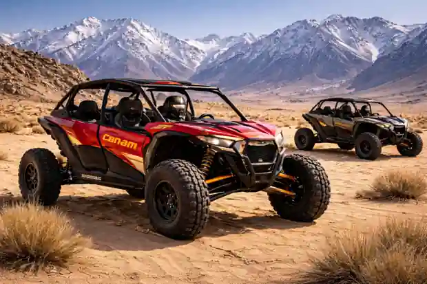 Can-Am dune buggies parked on rugged desert terrain with snow-capped mountains in the background