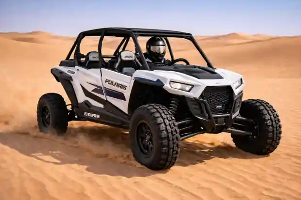 Polaris dune buggy driving across desert sand with rugged tires and helmeted rider